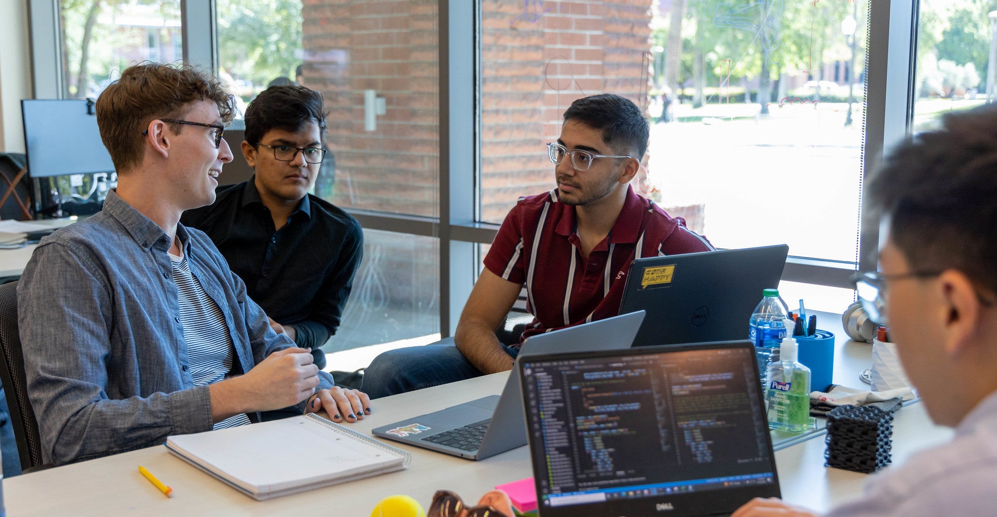 Students sit at a table to collaborate on their individual projects during a lab session.